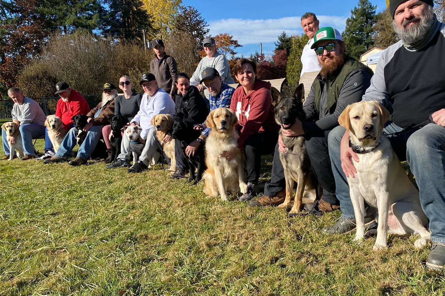 Several Veterans pose together with their service dogs