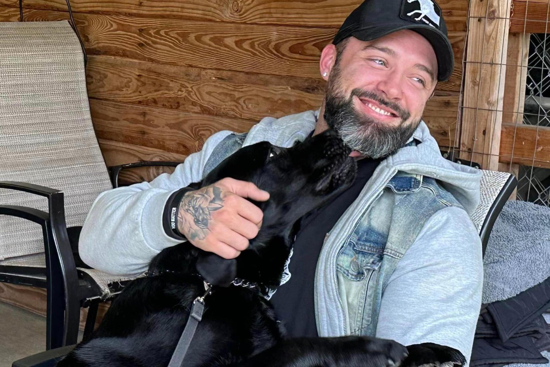 A Veteran holds a black lab in his lap 