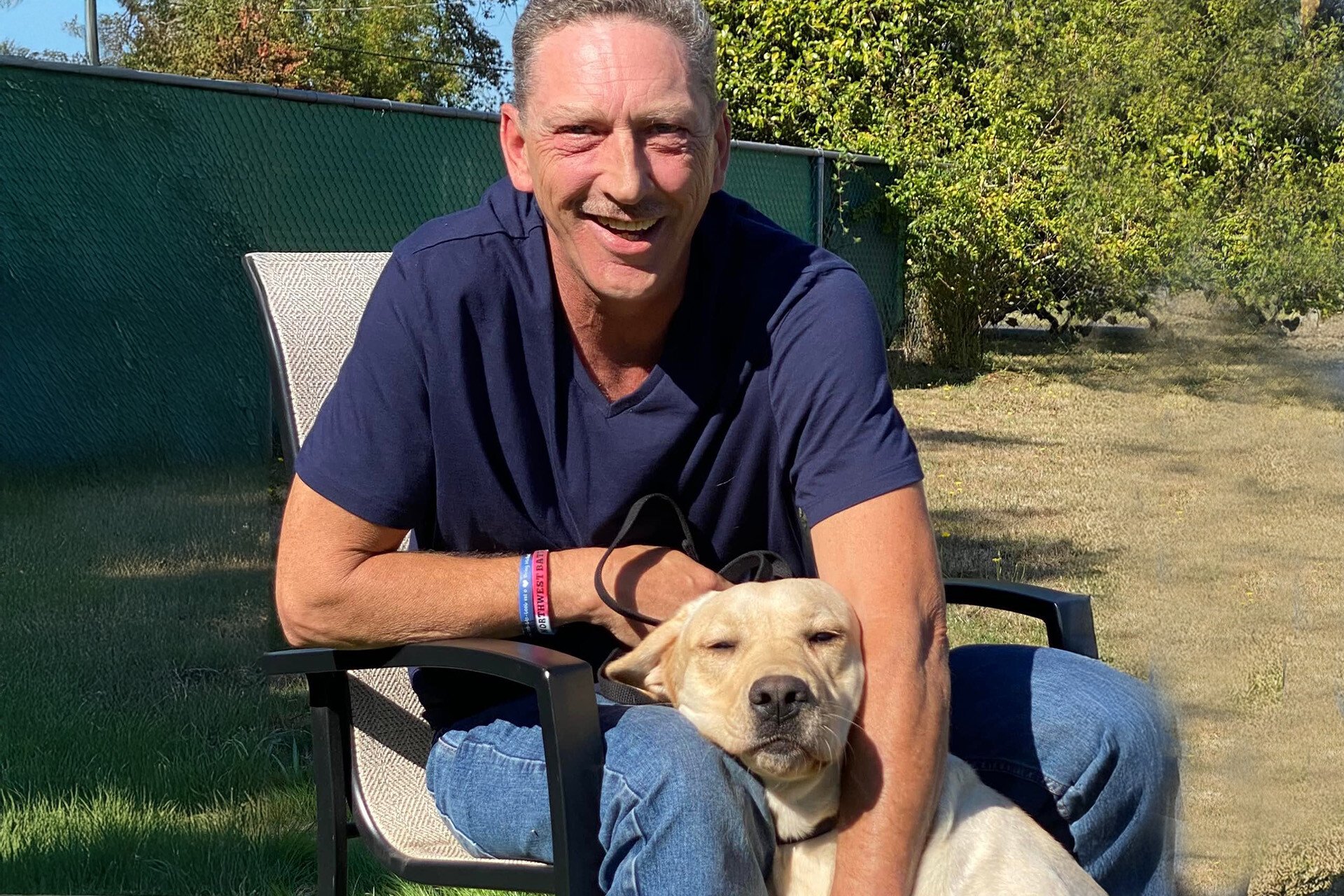 John sitting in a chair with dog Honey