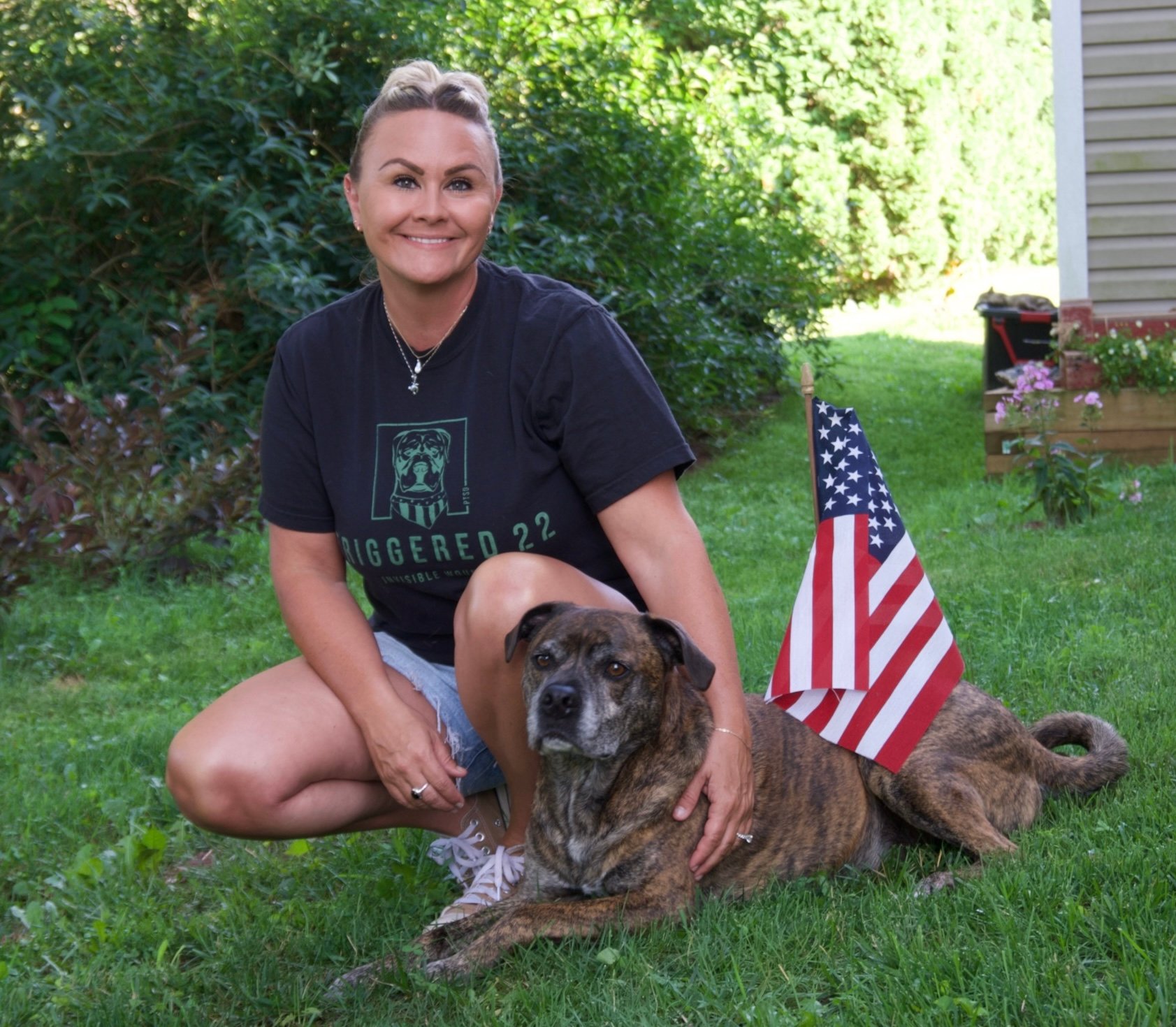 Rebekah with her service dog Trigger next to an American Flag